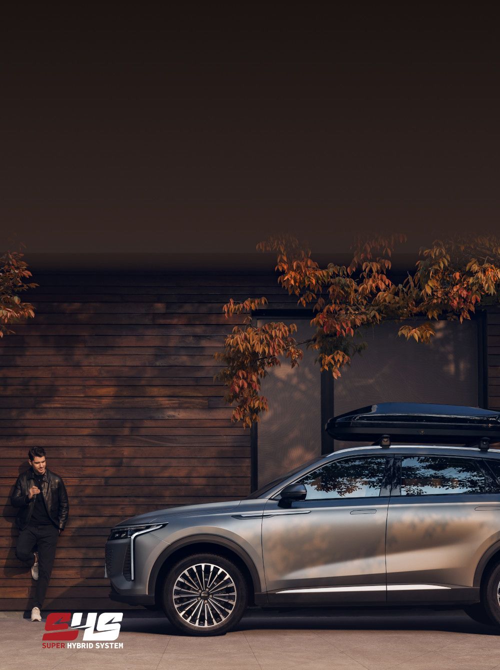 OMODA 9 PHEV mit Fahrer vor Holzfassade